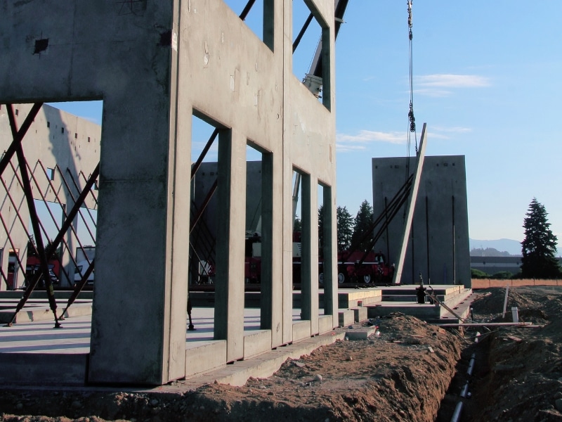 Partially built structure with reinforced concrete block walls supported by steel frames during construction on a commercial site.