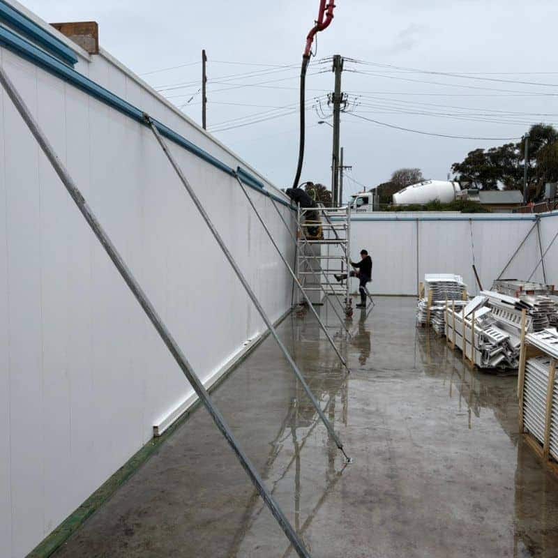 Wall water resistant formwork panels with bracing during concrete pour using pump hose on construction site