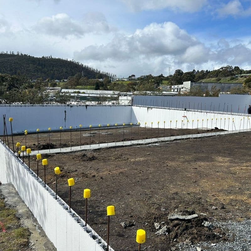 Retaining walls constructed with insulated formwork panels and vertical reinforcement rods on residential construction site