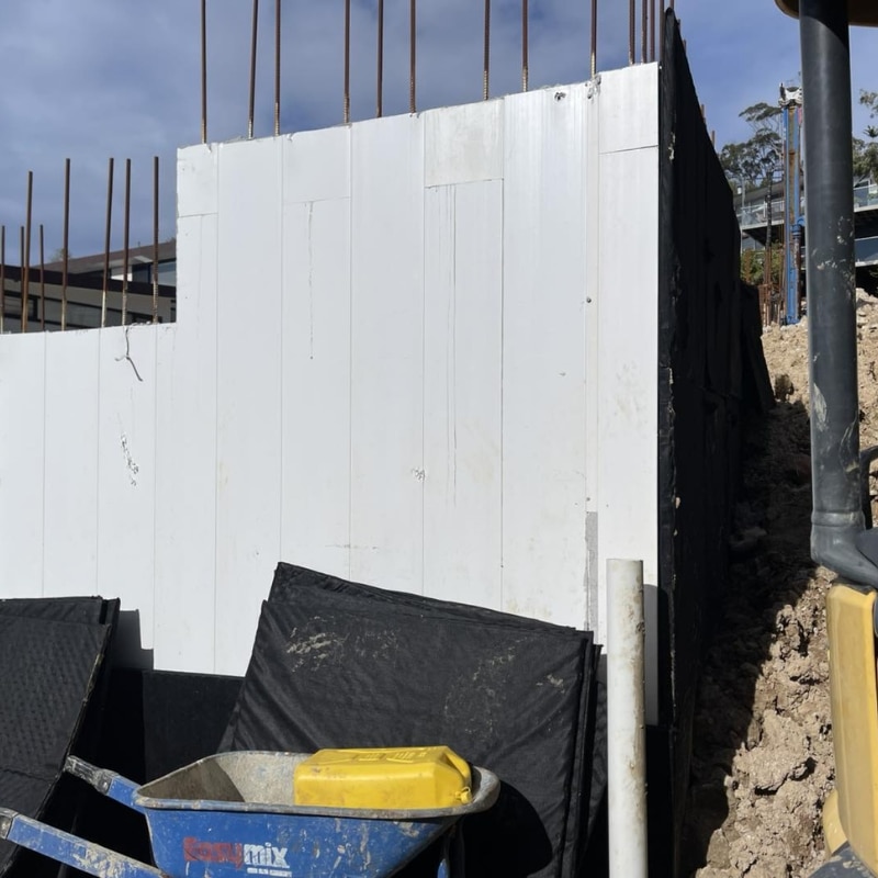 Installed lay flat formwork panels forming straight concrete wall with exposed reinforcement bars on construction site