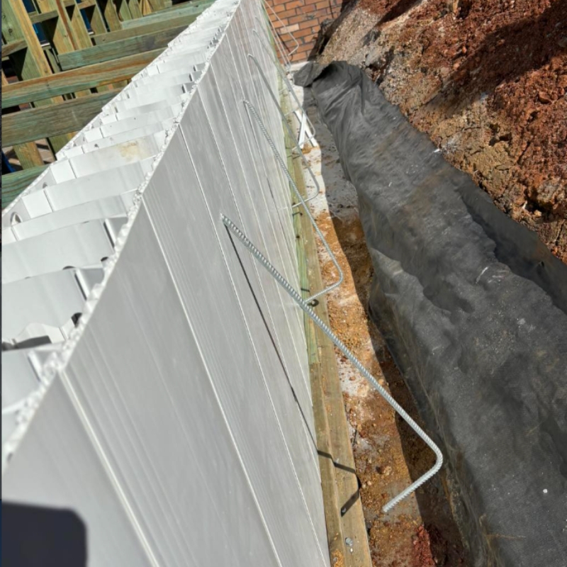 Construction of a modular retaining wall featuring reinforced paneling alongside a soil embankment to prevent erosion.