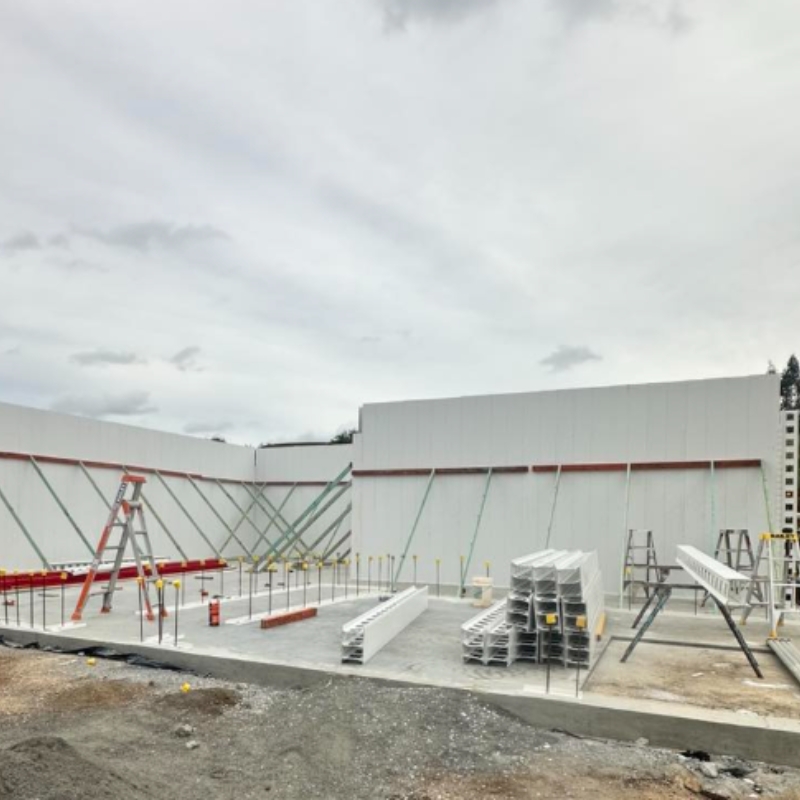 Large white precast concrete wall panels installed at a construction site, showcasing efficient building construction methods.