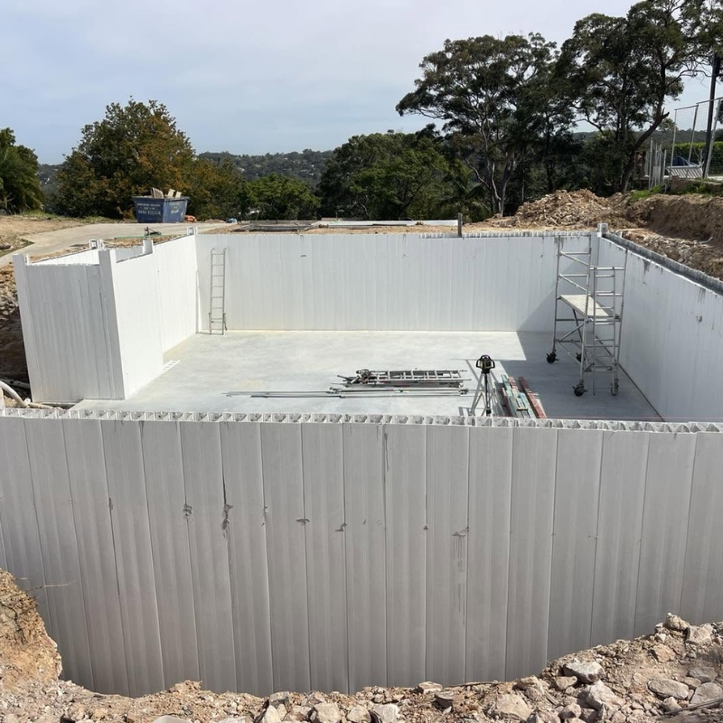 A structural white modular formwork system installed for a concrete basement wall at an excavation construction site.